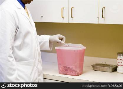 doctor putting a syringe in a toxic bin