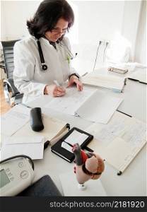 Doctor reading patients files at her desk