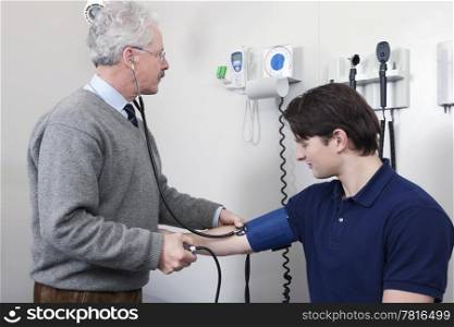 Doctor reading pulse rate while checking blood pressure of a young patient