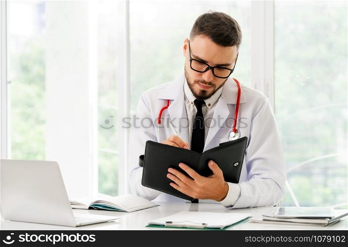 Doctor reading while writing note on a book at office in the hospital. Medical and healthcare concept.