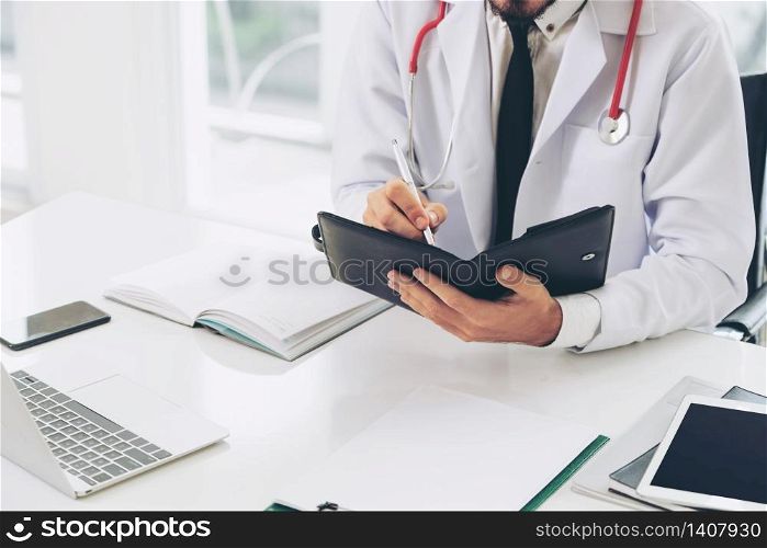 Doctor reading while writing note on a book at office in the hospital. Medical and healthcare concept.. Doctor reading while writing note on a book.