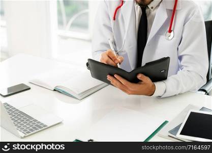 Doctor reading while writing note on a book at office in the hospital. Medical and healthcare concept.. Doctor reading while writing note on a book.