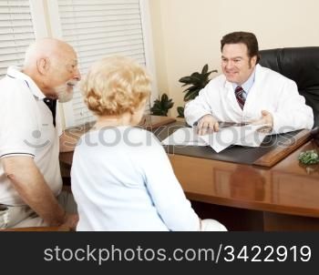 Doctor reviews the medical test results of a senior couple and gives them the good news.