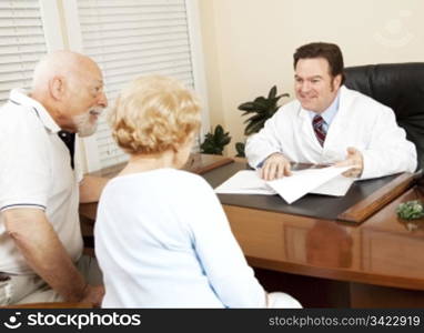 Doctor reviews the medical test results of a senior couple and gives them the good news.