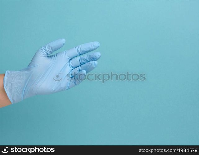 Doctor&rsquo;s hand in a blue medical glove holds an object on a blue background. Copy space, hold any object
