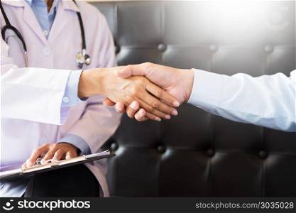 Doctor shakes hands at medical office with patient, wearing glasses, stethoscope and lab coat. Doctor shakes hands at medical office with patient, wearing glas