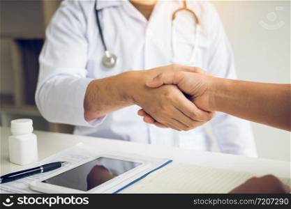 Doctor shaking hands with older patient in the clinic room.