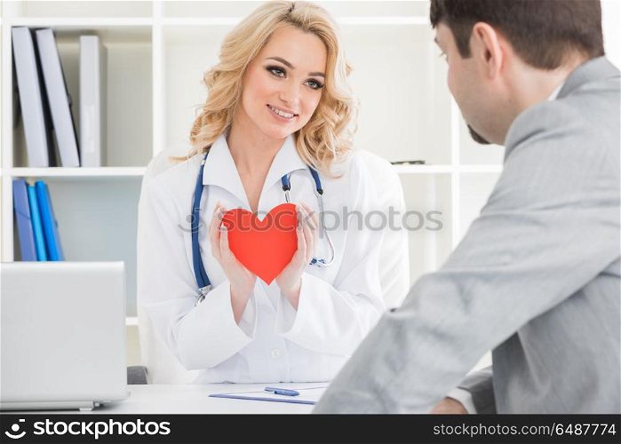 Doctor showing heart to patient. Doctor showing red paper heart to patient, cardio therapeutist consultation