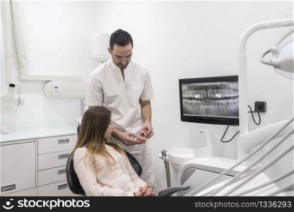 Doctor showing patient how clean teeth on teeth sample