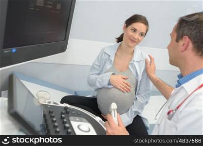 doctor showing pregant woman ultrasound