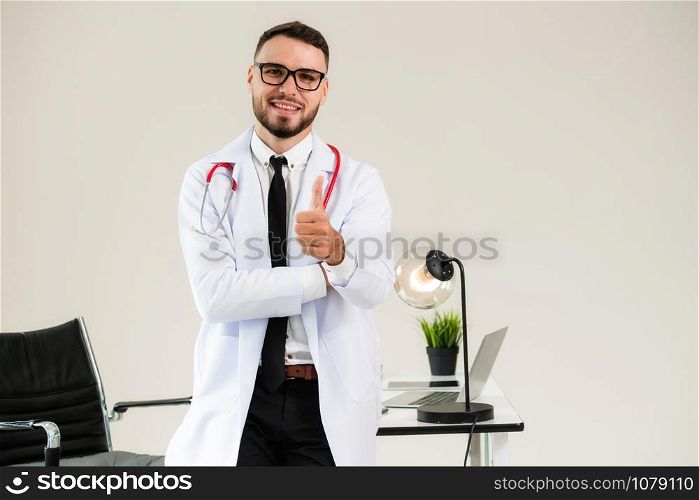 Doctor showing thumbs up while working at office table in the hospital. Medical and healthcare concept.