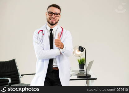 Doctor showing thumbs up while working at office table in the hospital. Medical and healthcare concept.