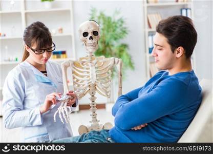 Doctor showing type of injury on skeleton to patient
