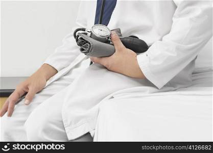 Doctor sitting and holding a blood pressure gauge