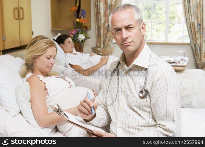 Doctor sitting by pregnant women holding chart