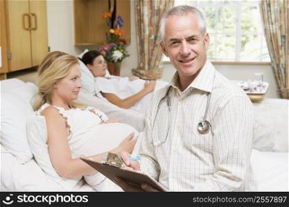 Doctor sitting by pregnant women holding chart and smiling