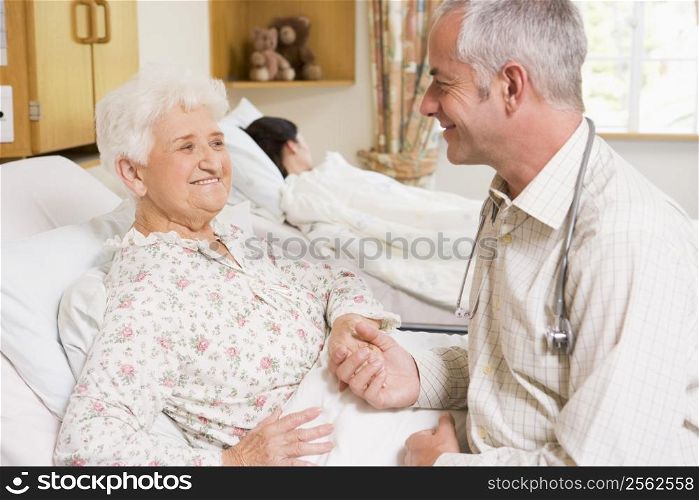 Doctor Sitting With Senior Woman In Hospital