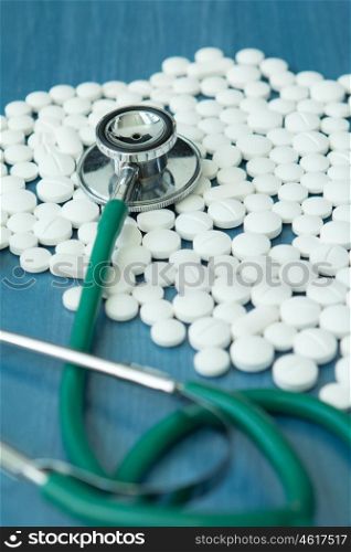 Doctor stethoscope and white pills on blue background