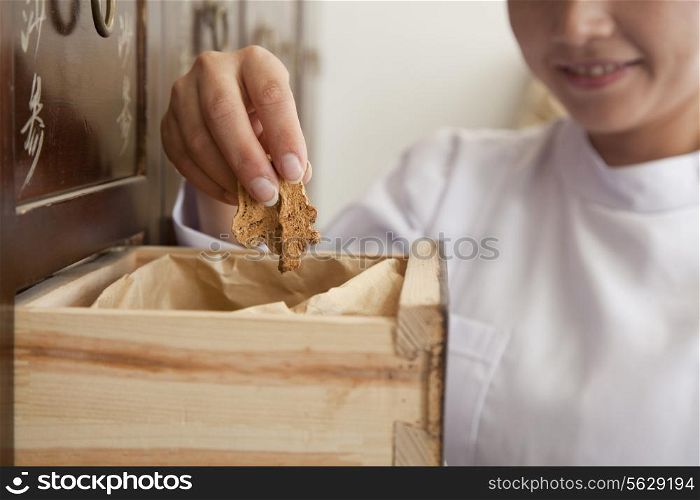 Doctor Taking Herb Used for Traditional Chinese Medicine Out of a Drawer