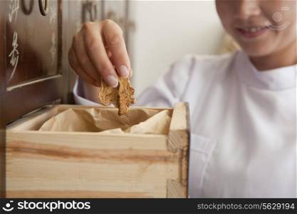 Doctor Taking Herb Used for Traditional Chinese Medicine Out of a Drawer