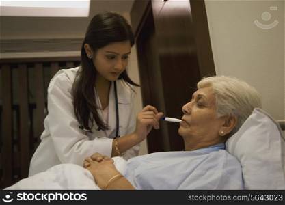 Doctor taking patient&rsquo;s temperature