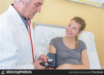 Doctor taking young lady's blood pressure