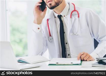 Doctor talking on mobile phone at office table in the hospital. Medical and healthcare concept.. Doctor talking on mobile phone hospital.