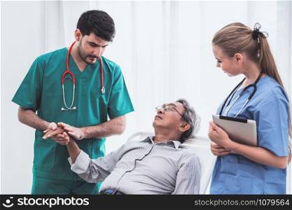 Doctor team taking care of senior adult man patient lying on bed in hospital ward. Medical healthcare staff service treatment concept.