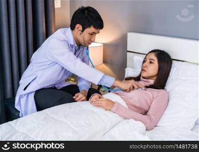 doctor use stethoscope to listen heart of female patient on a bed