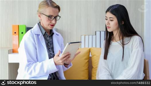 Doctor using digital tablet for explaining medication to woman patient and visit at home