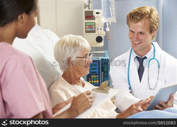 Doctor Using Digital Tablet In Consultation With Senior Female Patient In Bed