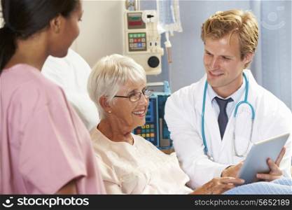Doctor Using Digital Tablet In Consultation With Senior Female Patient In Bed