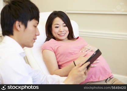 Doctor Using Digital Tablet In Meeting With Pregnant Woman