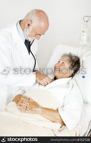 Doctor using his stethoscope to listen to an elderly hospital patient&rsquo;s heart.