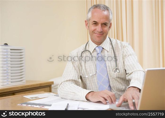 Doctor using laptop in doctor&acute;s office smiling
