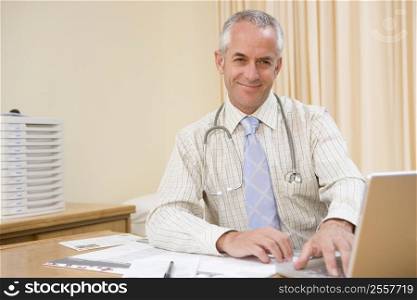 Doctor using laptop in doctor&acute;s office smiling