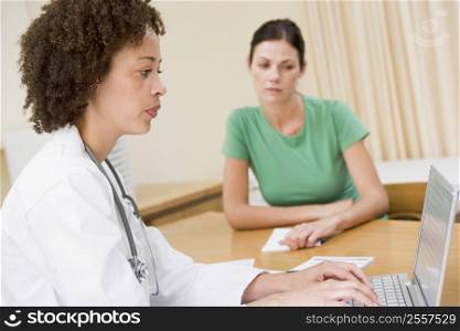 Doctor using laptop with woman in doctor&acute;s office frowning