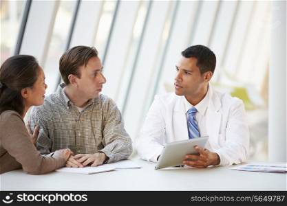 Doctor Using Tablet Computer Discussing Treatment With Patients