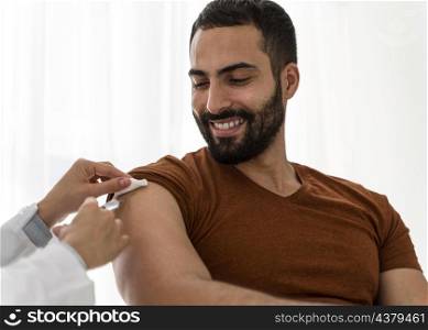 doctor vaccinating handsome smiley man