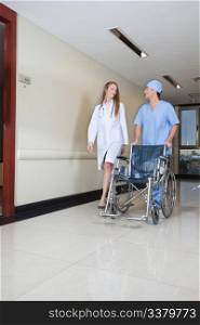 Doctor walking with male nurse pushing wheelchair