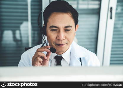 Doctor wearing headset talking actively on video call in a clinic or hospital . Concept of telehealth and telemedicine service .. Doctor wearing headset talking actively on video call in a clinic or hospital .