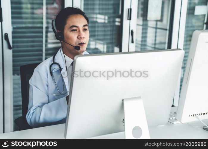 Doctor wearing headset talking actively on video call in a clinic or hospital . Concept of telehealth and telemedicine service .. Doctor wearing headset talking actively on video call in a clinic or hospital .