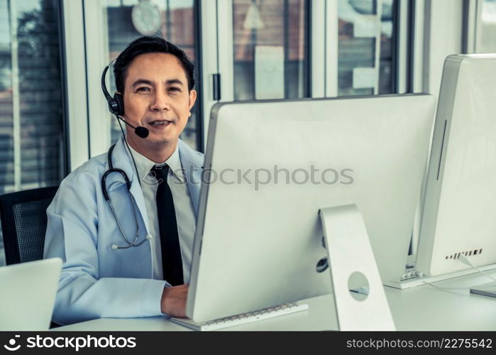 Doctor wearing headset talking actively on video call in a clinic or hospital . Concept of telehealth and telemedicine service .. Doctor wearing headset talking actively on video call in a clinic or hospital .