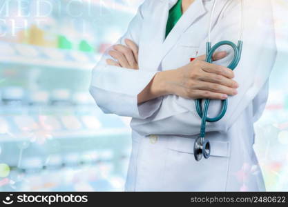 Doctor wears white uniform. Physician stand with arms crossed and hand holding stethoscope. Healthcare professional. Doctor stand with confidence on blurred drug shelves and drug chemical structures.