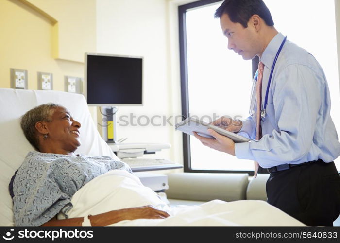 Doctor With Digital Tablet Talks To Woman In Hospital Bed