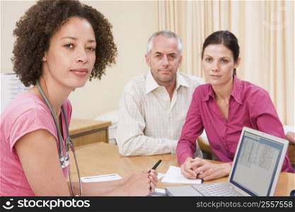 Doctor with laptop and couple in doctor&acute;s office