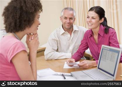 Doctor with laptop and couple in doctor&acute;s office smiling