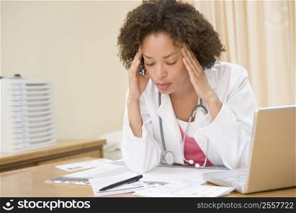 Doctor with laptop and headache in doctor&acute;s office