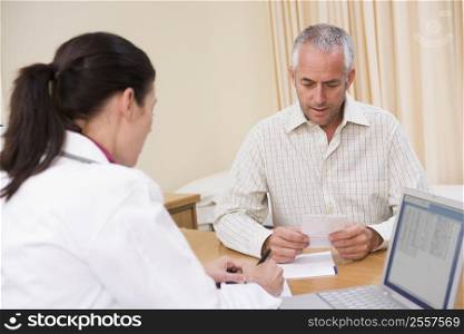 Doctor with laptop and man in doctor&acute;s office