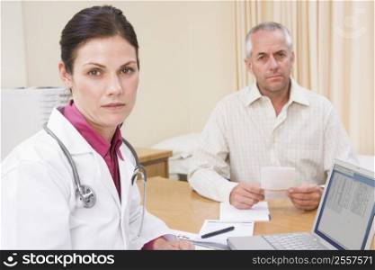 Doctor with laptop and man in doctor&acute;s office frowning
